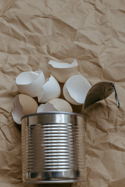 蛋壳在锡顶视图。创意的静物照片，蛋壳在一个锡罐在棕色的背景。图片下载
