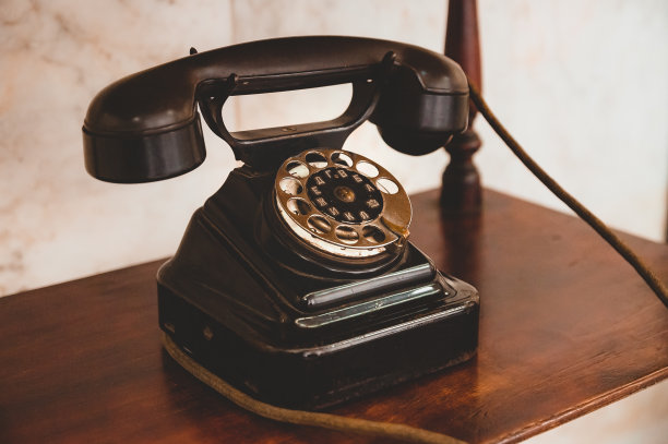 架子上有一部带电线的旧电话。图片下载