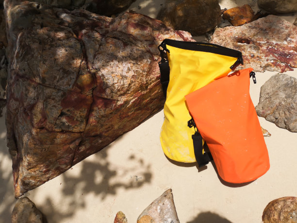 沙滩上的橙色和黄色防水包。海上旅行用防水袋。图片下载