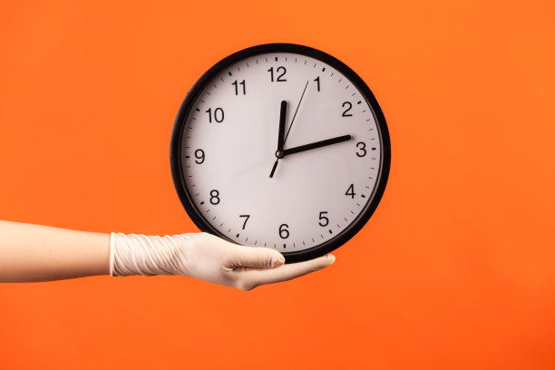 侧面特写的人手在白色外科手套拿着模拟钟。图片下载