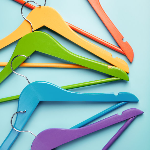 5个儿童衣架，用来挂五颜六色的衣服。蓝色背景。图片下载
