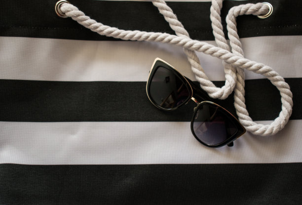 女人的太阳镜在白色和黑色的沙滩包图片下载