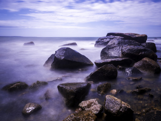 长时间暴露的海景与白色的波浪流过岩石在海滩上图片下载