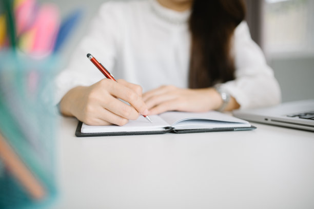 女人的手拿着笔在书上写字图片下载