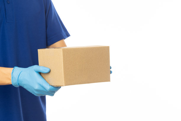 近距离送货员手在医疗手套持有纸板盒隔离在白色背景，包装模型，送货服务概念图片下载