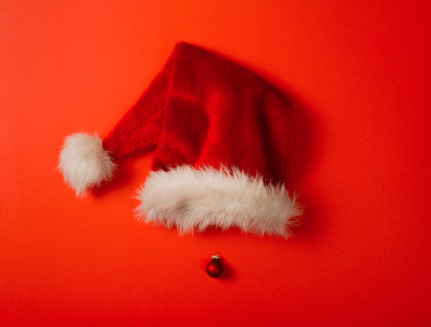 红色的圣诞老人帽子和圣诞树玩具做鼻子。红色的背景。圣诞节，新年和寒假的概念照片。图片下载