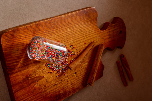 彩色的糖果和糖果从玻璃洒在旧的厨房木板上，肉桂棒。艺术照片选择焦点。圣诞节，烹饪，厨房，食物和家庭烘焙概念照片。图片下载