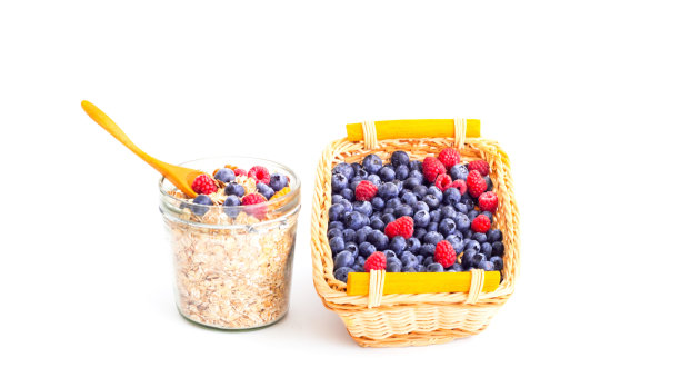 在白色背景下，玻璃罐中有蓝莓和覆盆子的什锦麦片。生态产品的概念。图片下载