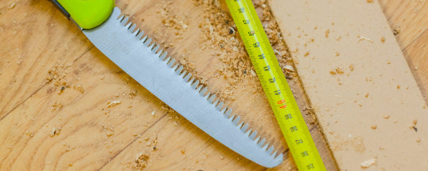 黄色卷尺和锯末间的锯，近距离看，背景模糊图片下载
