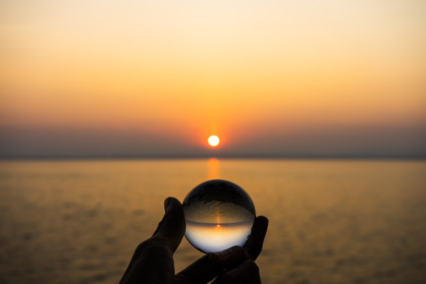 湖边落日的天空中，手握水晶的剪影。图片下载