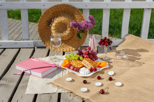 静物和食物照片。一盘水果、一杯水和一瓶紫丁香放在木地板上的粗麻袋上图片下载