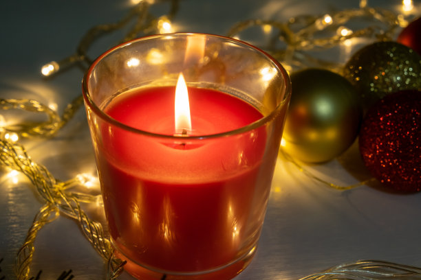红色圣诞蜡烛，在桌子上燃烧的蜡烛火与节日花环，松树装饰和球图片下载