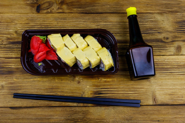 寿司芝士卷在塑料盒里放在木桌上。前视图。装在塑料容器内的寿司供外卖或运送图片下载