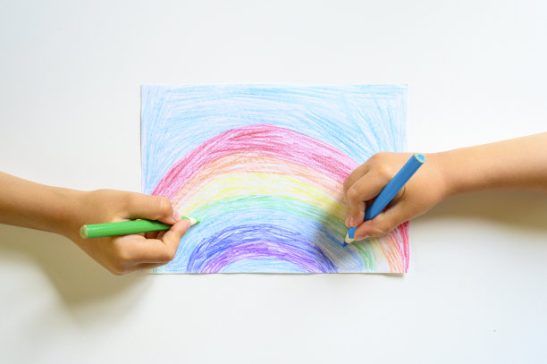 小朋友双手一起在白色的背景上画彩虹色的铅笔图片下载