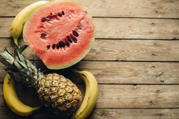 木地板上放着西瓜、黄色香蕉和菠萝。处理空间。水果的背景。图片下载