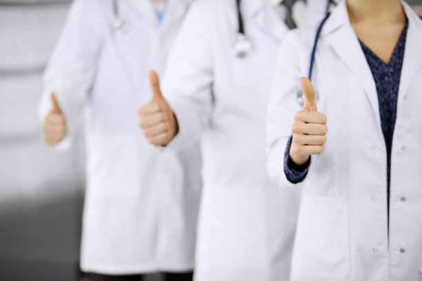 医生们站成一个团队，在诊所里竖起大拇指，随时准备帮助病人。医疗帮助，保险和医学概念图片下载
