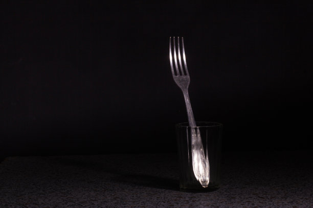 叉子放在杯子里，背景是黑色。摄影工作室图片下载