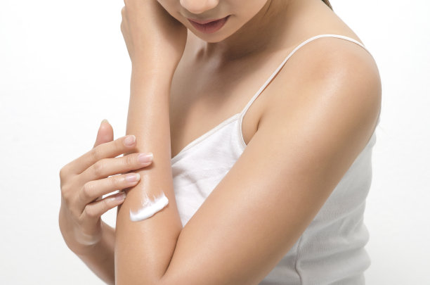 年轻女子在白色背景上涂抹身体霜图片下载