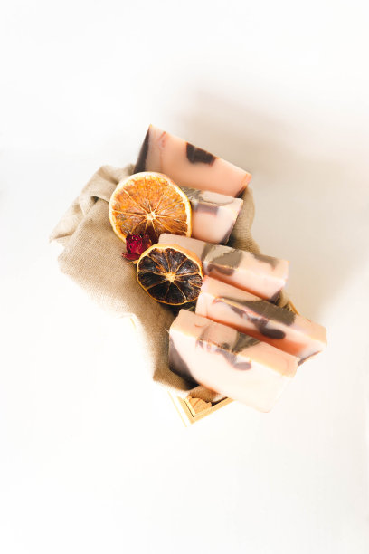 五块带橙色的棕粉色手工肥皂、干橙子片和干玫瑰，放在一个木质的白色背景上。水平照片，复制空间的文本。手工化妆品的概念与自然图片下载