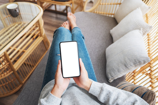 一名女子躺在沙发上，手里拿着手机，手机屏幕是空白的图片下载
