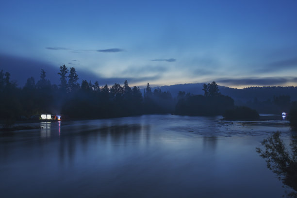 夜间景观:宽阔的河流，针叶林和天空与云彩。图片下载