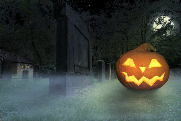 一个可怕的咧嘴笑的万圣节南瓜躺在一个雾蒙蒙的墓地上素材图片