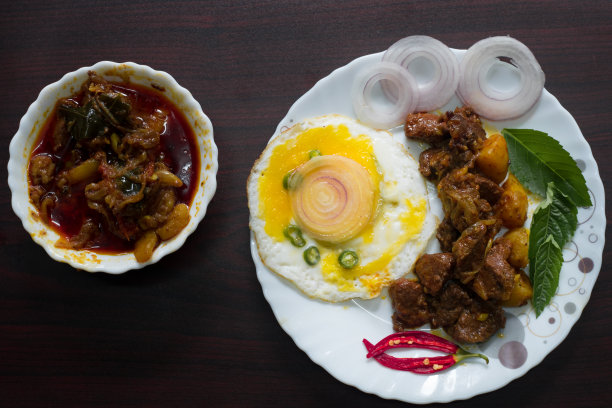 美食摄影，牛眼，鸡蛋配上辣椒和洋葱，看起来很好吃。以切菜桌、刀和汤匙作背景装饰。图片下载