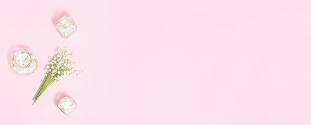 小百合花山谷和玻璃瓶与干花瓣在软粉红色的背景与文本复制空间。春季和芳香疗法。水疗中心平面。图片下载