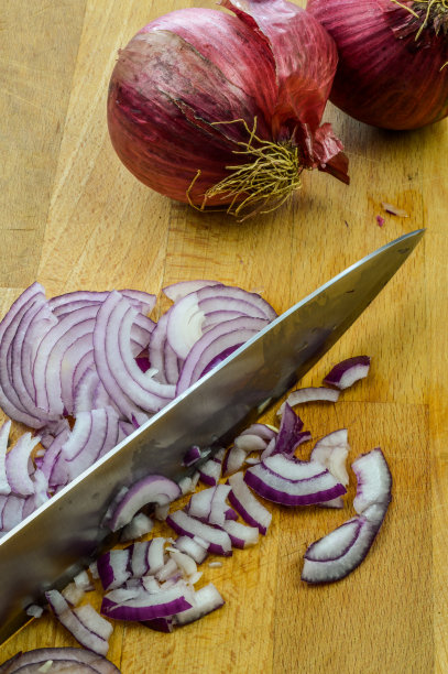用菜刀在木砧板上切红洋葱，特写，切红洋葱。图片下载