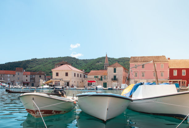 在赫瓦尔的斯塔格雷德港，古老的简单的船只停靠在海滨。在城市广场的背景下，古老的石屋和教堂钟楼拔地而起图片下载