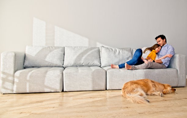 一对夫妇和金毛猎犬在沙发上休息图片下载