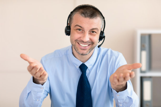 戴耳机的成熟男子坐在办公室接听客户来电图片下载