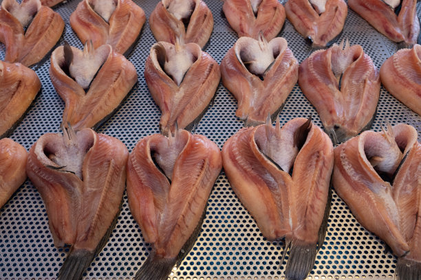 在当地市场，一排排晒干的黑鱼陈列在开槽的不锈钢托盘上。图片下载