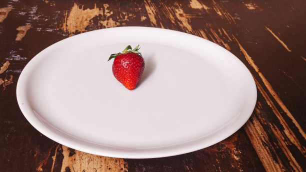 木桌上白色的盘子里放着成熟的红草莓。从以上观点。图片下载