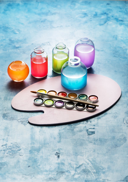 玻璃瓶里的彩色水彩颜料和画家的调色板。创造性的艺术背景图片下载