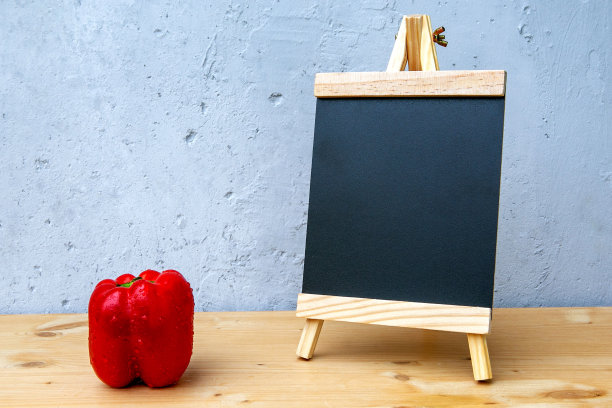 灰色背景的木桌上，小黑板和红辣椒图片下载