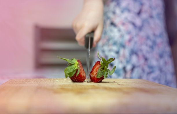 在切好的木板上对焦切一个草莓。图片下载