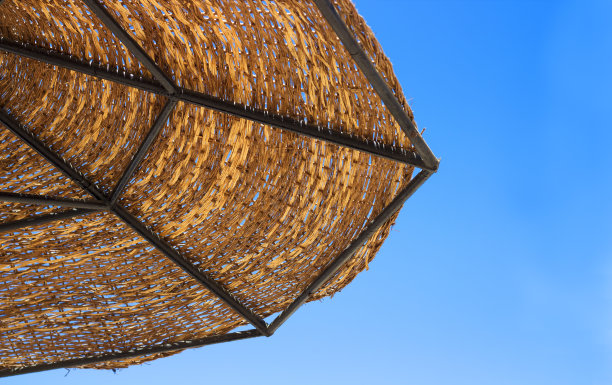 沙滩上的草伞以蓝天为背景图片下载