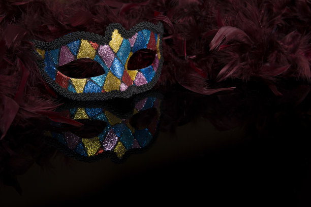彩色面具与羽毛围巾在黑色的背景图片下载