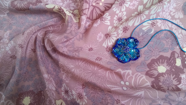 粉色丝绸面料上的深蓝色水晶吊坠闪闪发光图片下载