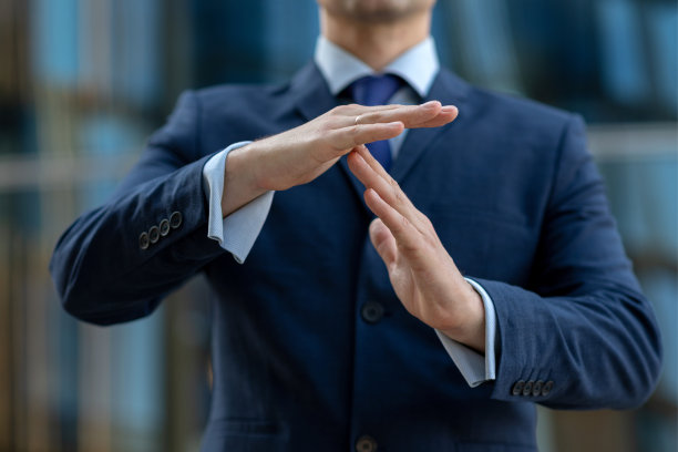 蓝色西装商人制作的暂停手势。关闭视图图片下载