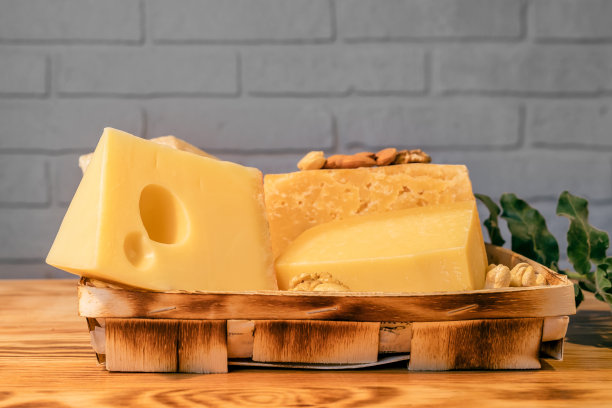靠砖墙的木桌上放着各种陈年奶酪图片下载