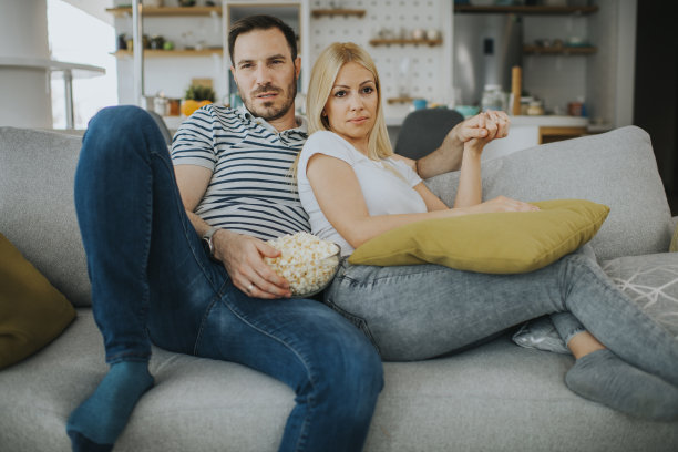 年轻夫妇在家里看电视库存照片图片下载