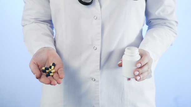 医生从蓝色背景的瓶子里倒出药丸图片下载