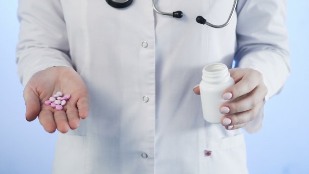 医生，拿着粉红色的药丸和蓝色背景上的瓶子图片下载