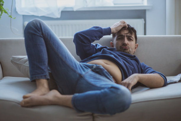 一个男人宿醉后躺在沙发上。图片下载