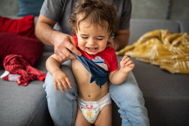 成年男子试图给小孩换衣服图片下载
