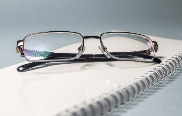 眼镜放在一个白色笔记本上，灰蓝色的背景。学习研究的概念图片下载