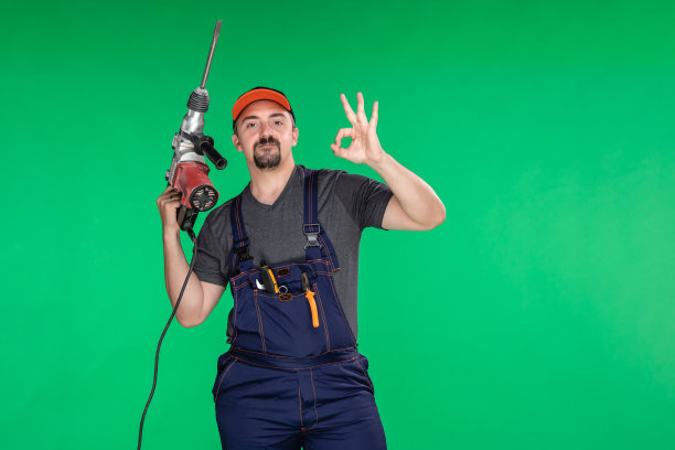 建筑工人用钻床在绿色背景上显示OK标志图片下载