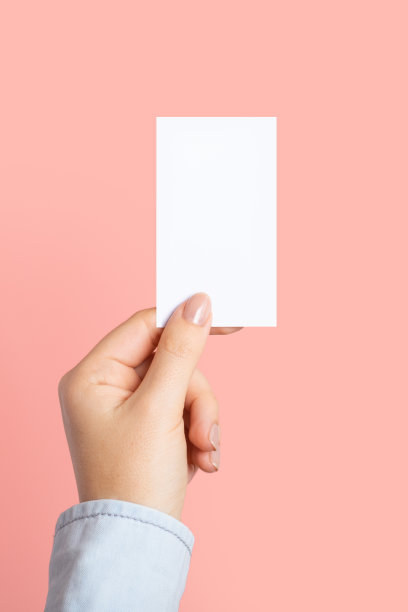女性的手与切成圆角，空白菜单，折扣卡，名片上的颜色粉红色美丽的背景与复制空间。模板的设计。垂直图图片下载